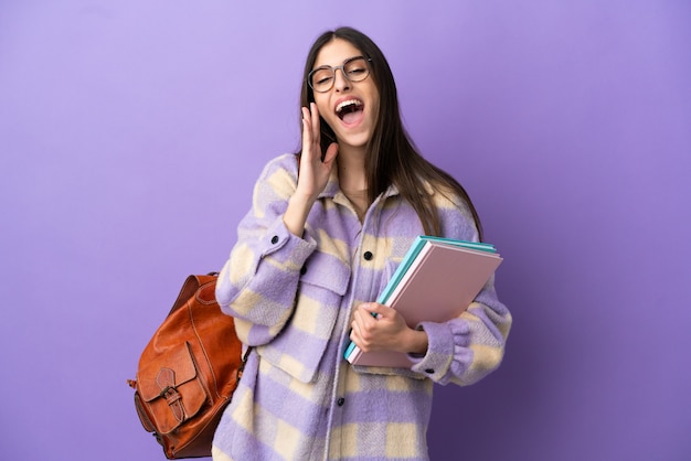 Young student woman isolated on purple background shouting with mouth wide open