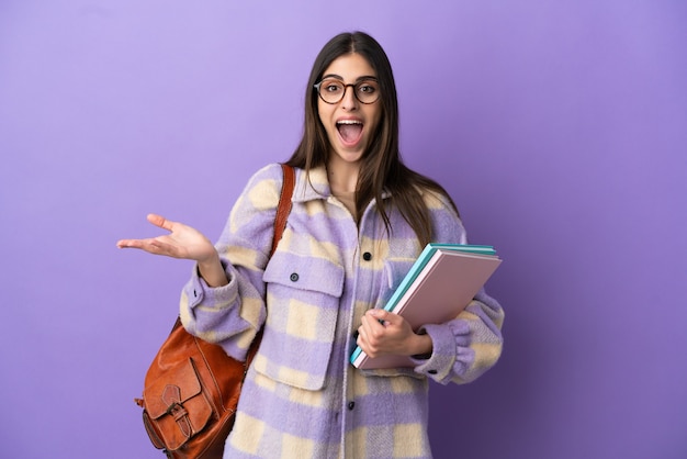 Young student woman isolated on purple background with shocked facial expression