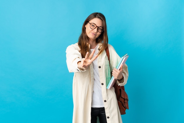 Young student woman over isolated wall happy and counting three with fingers