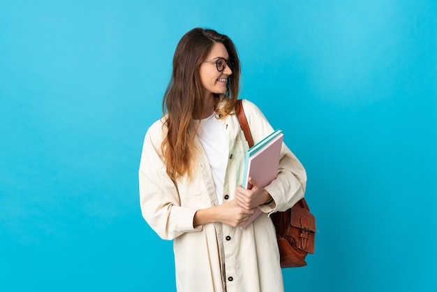 Young student woman over isolated wall looking to the side and smiling