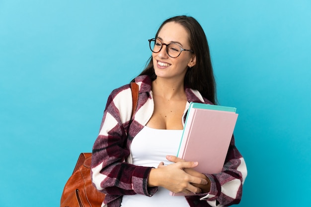 横を見て笑っている孤立した壁の上の若い学生女性