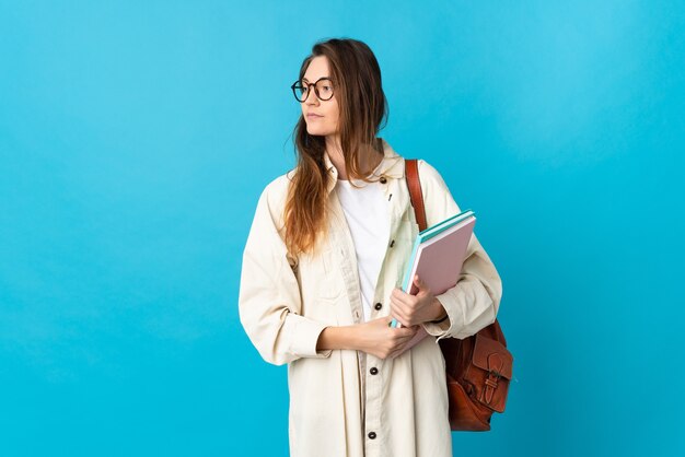 Young student woman over isolated wall looking to the side