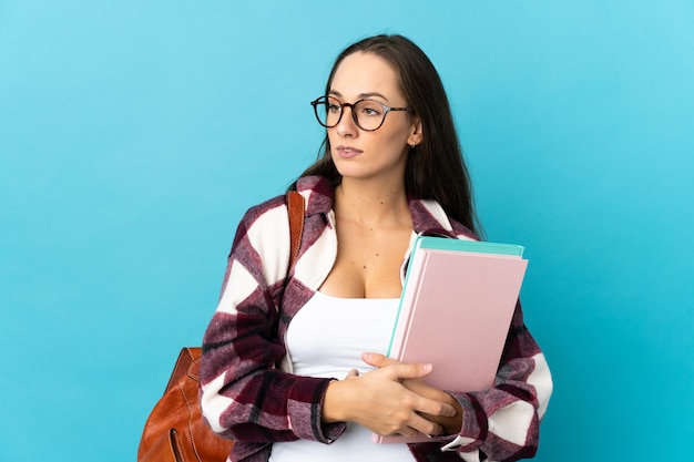 Young student woman over isolated wall looking to the side