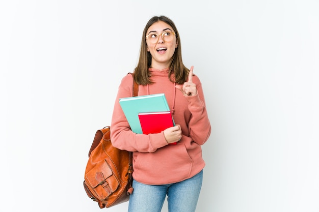 Young student woman isolated on white bakcground pointing upside with opened mouth.