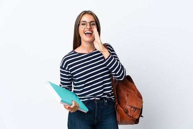 Young student woman isolated on white wall shouting with mouth wide open