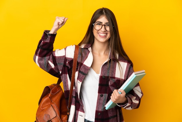 Young student woman isolated on yellow background doing strong gesture