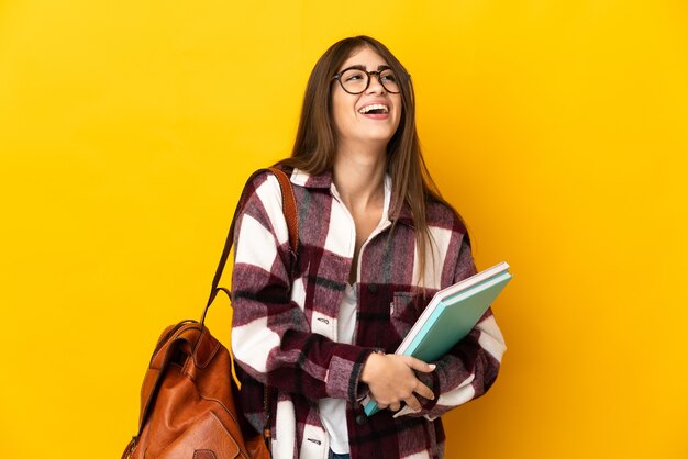 Young student woman isolated on yellow background laughing