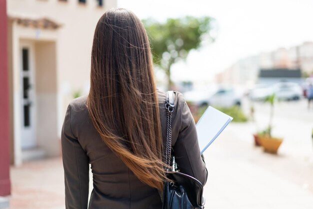 屋外でバックの位置で若い学生の女性