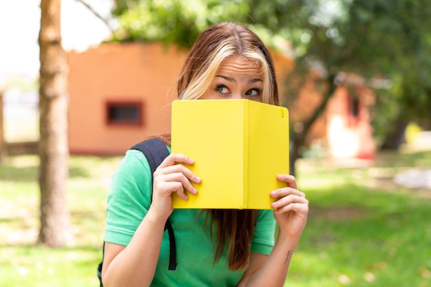 ノートを持って屋外で若い学生女性