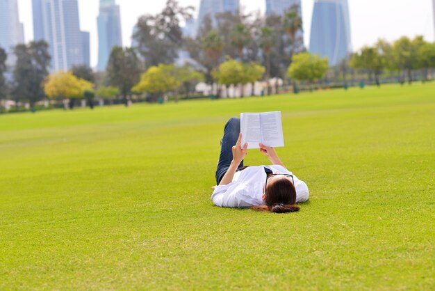 本を読んで公園で勉強する若い学生女性