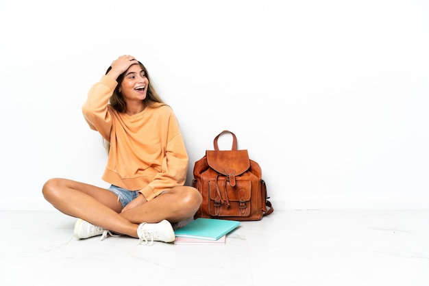 Young student woman sitting on the floor with a laptop isolated