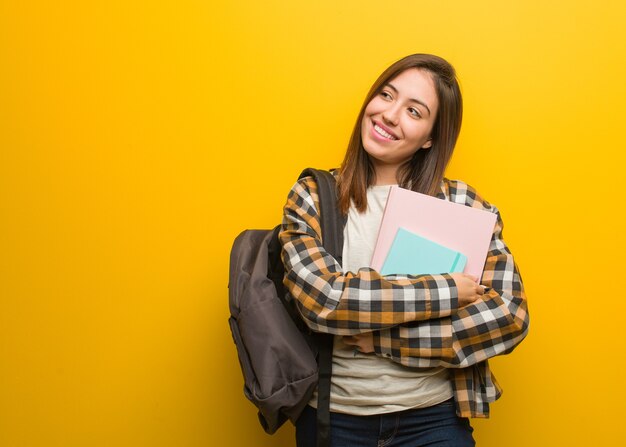 Young student woman smiling confident and crossing arms, looking up