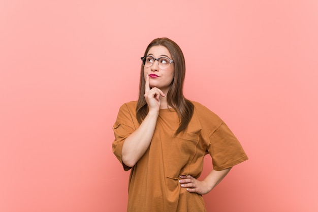 Young student woman wearing eyeglasses looking sideways with doubtful and skeptical expression.