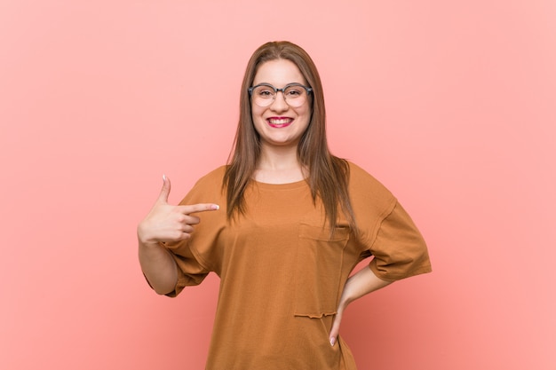 Young student woman wearing eyeglasses person pointing by hand to a shirt copy space, proud and confident