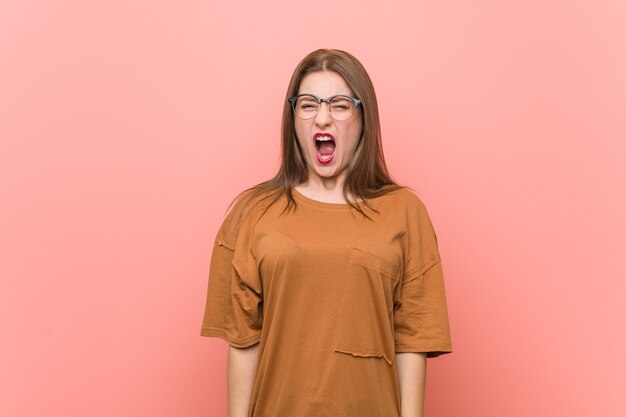 Young student woman wearing eyeglasses screaming very angry and aggressive.