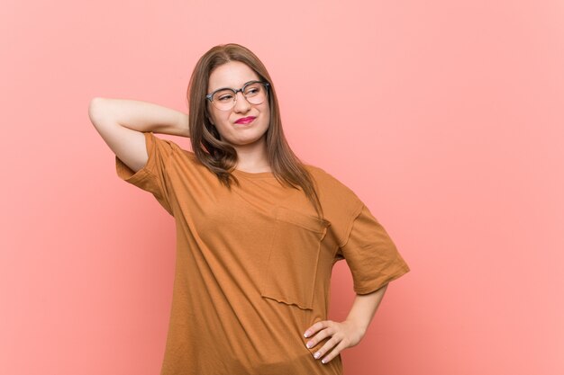 Young student woman wearing eyeglasses touching back of head, thinking and making a choice.