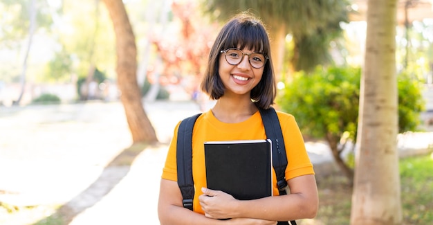 Young student woman win a park holding a notebook