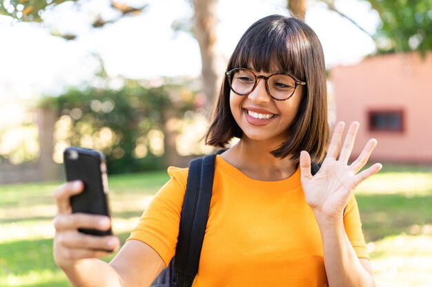 Young student woman win a park using mobile phone