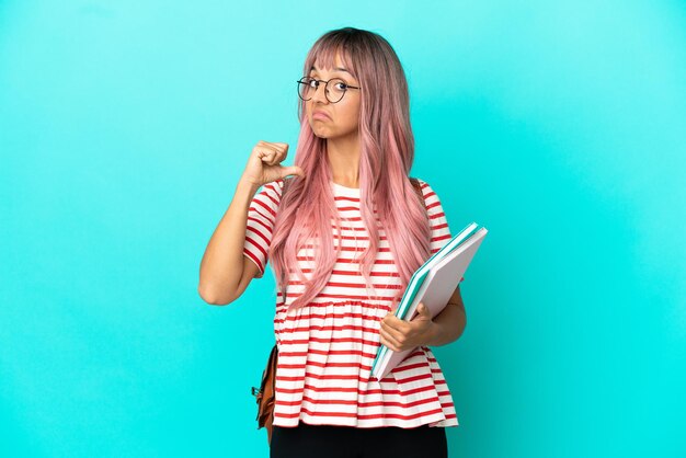 Young student woman with pink hair isolated on blue background proud and self-satisfied