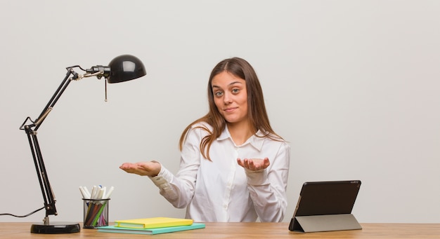 Foto donna giovane studente che lavora alla sua scrivania confusa e dubbiosa