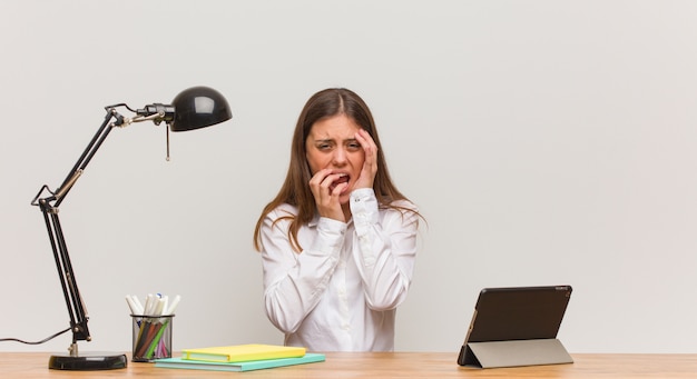 Young student woman working on her desk desperate and sad