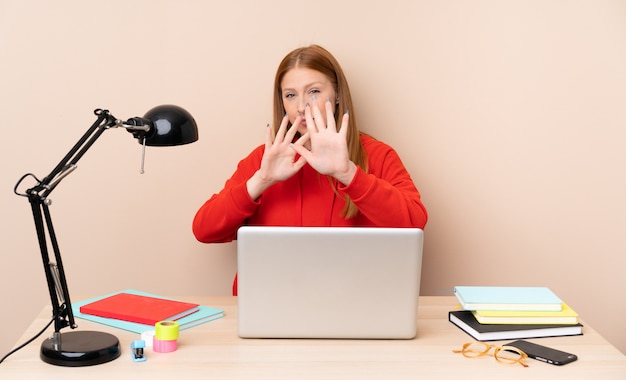Giovane donna dello studente in un posto di lavoro con un computer portatile che allunga nervosamente le mani alla parte anteriore