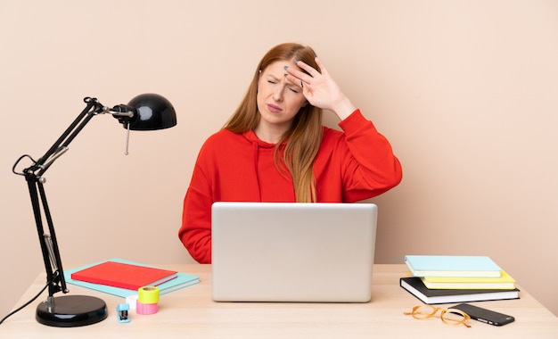 Young student woman in a workplace with a laptop with tired and sick expression