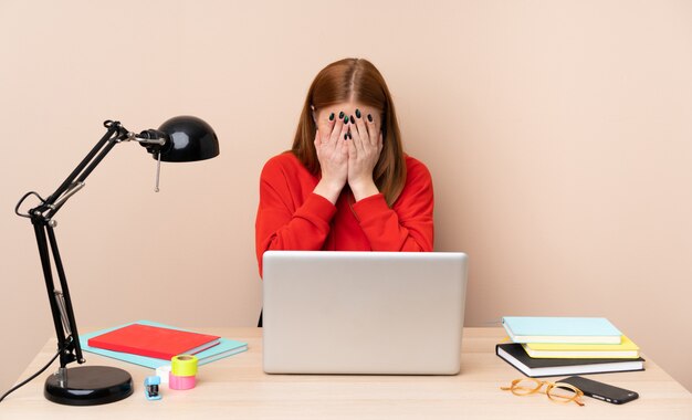 Young student woman in a workplace with a laptop with tired and sick expression