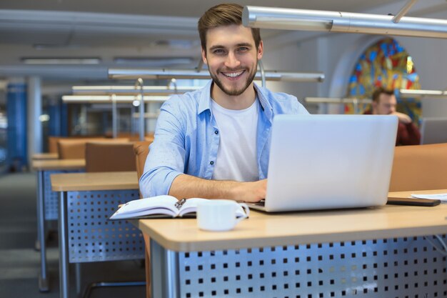 図書館でラップトップに取り組んでいる若い学生。