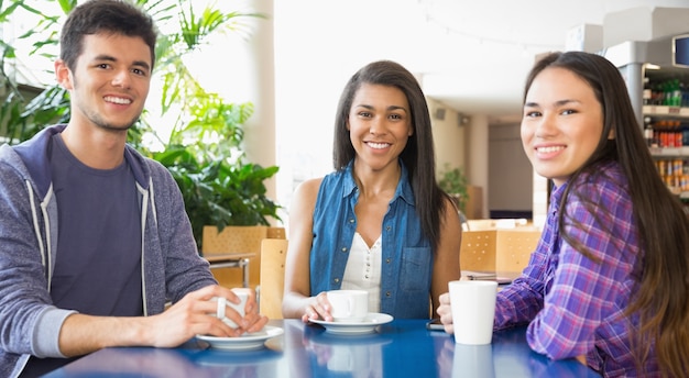 Young students smiling at camera in cafe