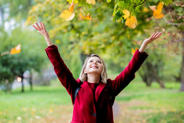 Young style girl with leaves in park alley