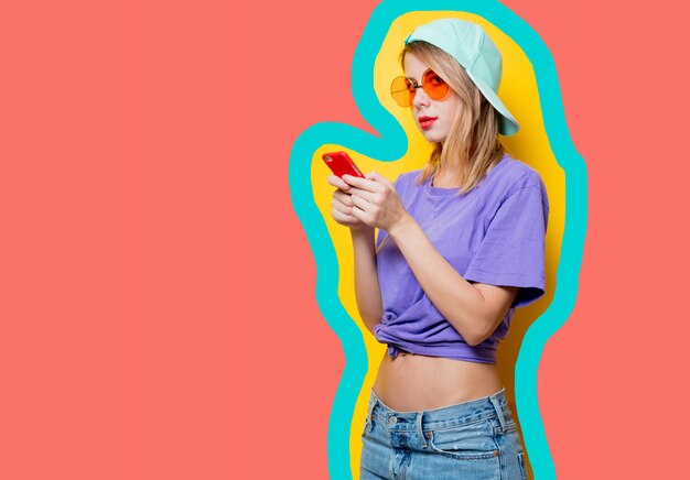 描かれた生きているサンゴ色の背景に携帯電話を持つ若いスタイルの女の子。 2019年のパントントレンド
