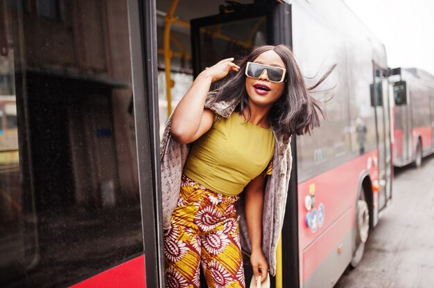 Young stylish african american woman in modern sunglasses riding on a bus.