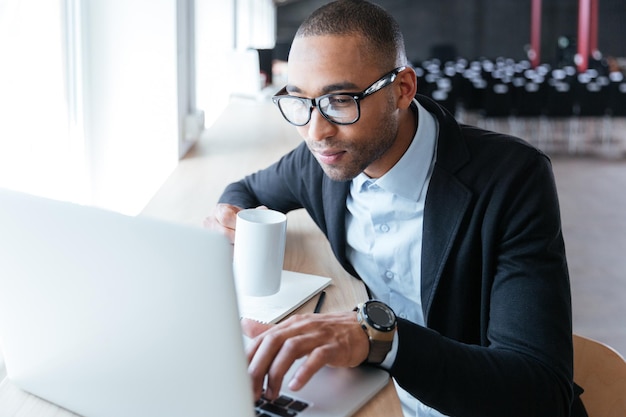 Giovane uomo d'affari alla moda che lavora utilizzando il computer portatile in ufficio