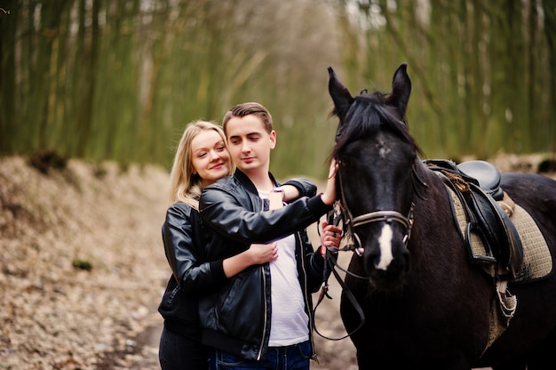 Young stylish couple in love near horse at autumn forest