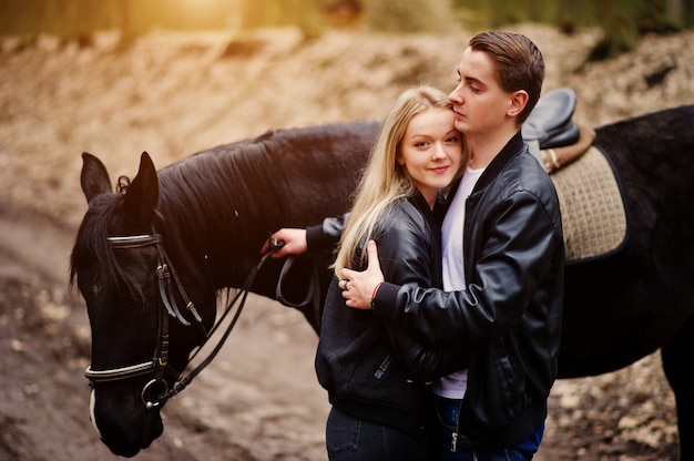 Young stylish couple in love near horse at autumn forest