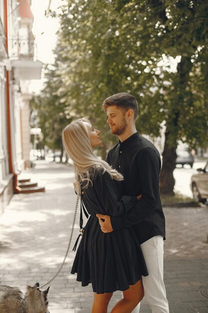 Young stylish couple walking with dog in street