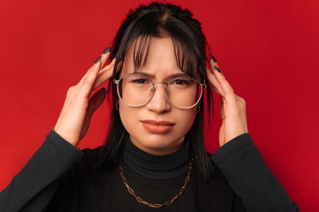 Young stylish frowning woman touching her head while having a bad headache