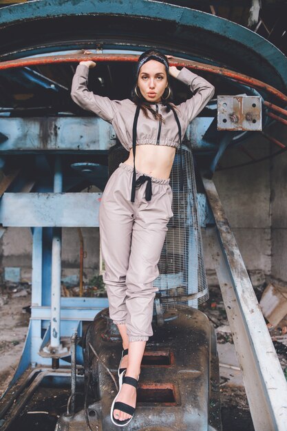 Young stylish girl posing at abandoned factory outdoor.