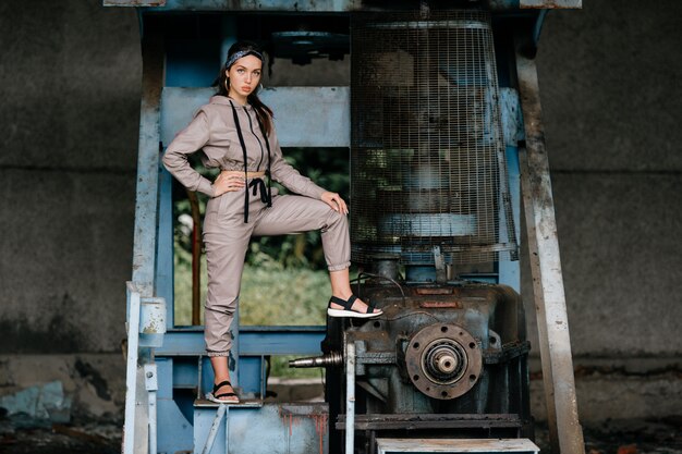 Young stylish girl posing near old mechanism outdoor.