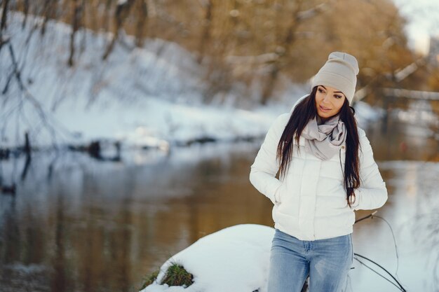 young and stylish girl snadning in a winter snowy park neaw water