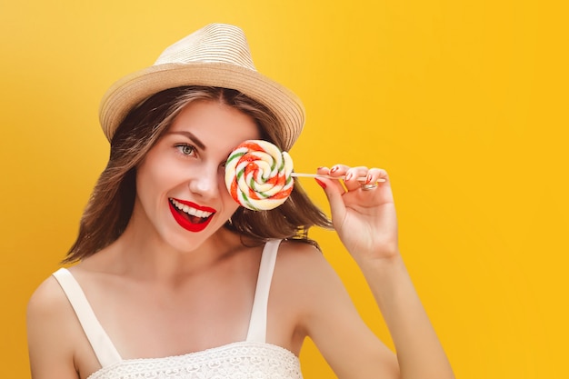 Young stylish girl in a straw hat with a rainbow lollipop. Summer concept