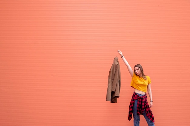 Young stylish girl throws out on orange background