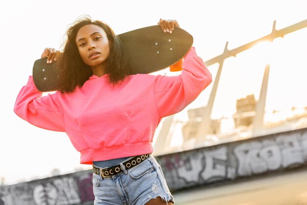 Young stylish girl with skateboard standing outdoors Urban lifestyle shot