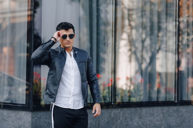 Young stylish guy in glasses in black leather jacket 