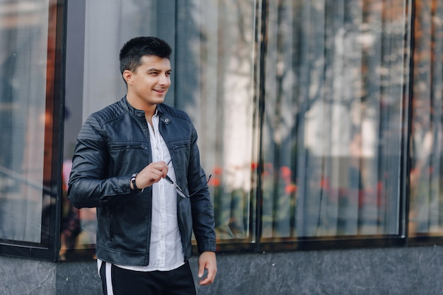 Young stylish guy in glasses in black leather jacket