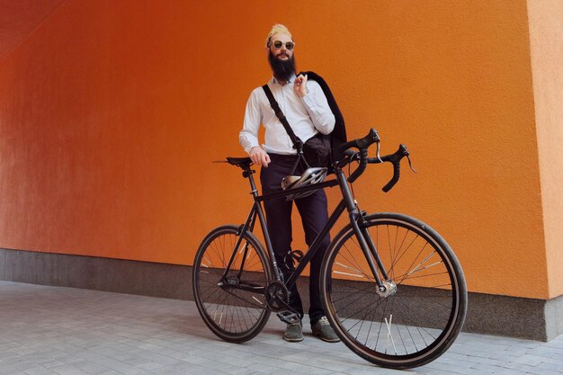 A young stylish hipster posing next to his bicycle