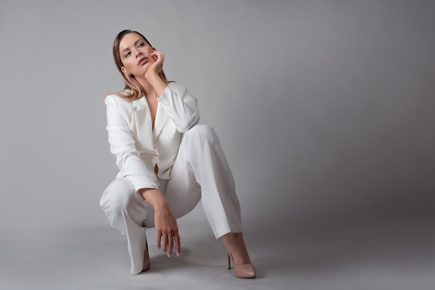 Giovane signora alla moda in un ritratto di tailleur pantalone bianco in studio