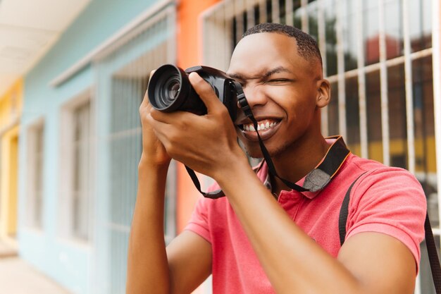 街を探索しながらカメラを使用する若いスタイリッシュな男性写真家 写真家世界デーのコンセプト