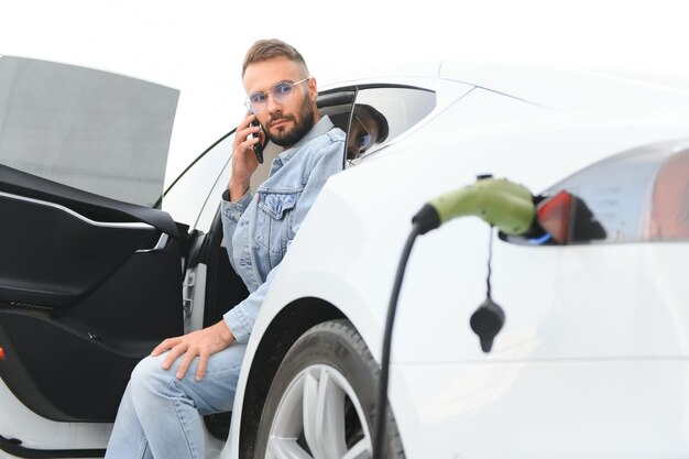 Young stylish man is with electric car at daytime The concept of green energy